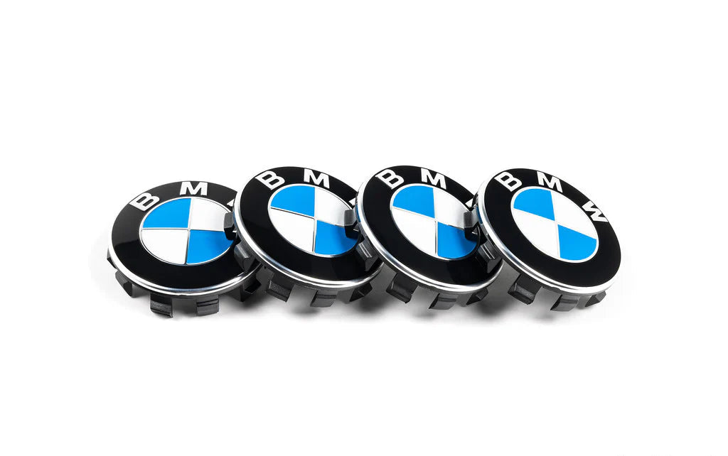 Four BMW car wheel hub caps on a white background