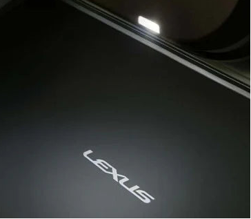Car door open with Lexus logo illuminated on a dark floor mat